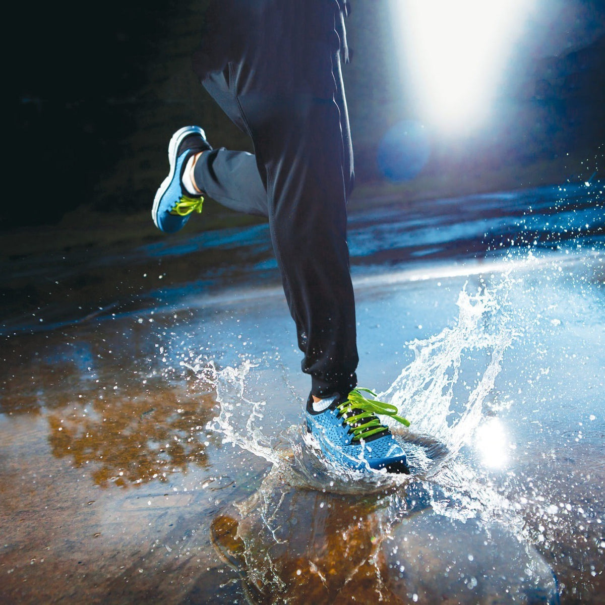 Läufer mit Sportschuhen in einer Wasserpfütze