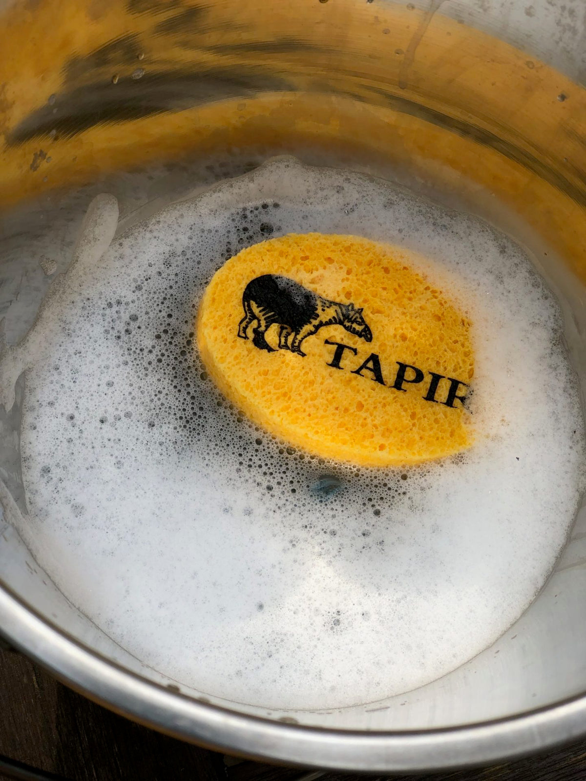 Gelber Tapir-Reinigungsschwamm in schäumendem Wasser