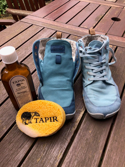 Tapir-Reiniger und Schwamm neben blauen Textilschuhen auf einem Holztisch
